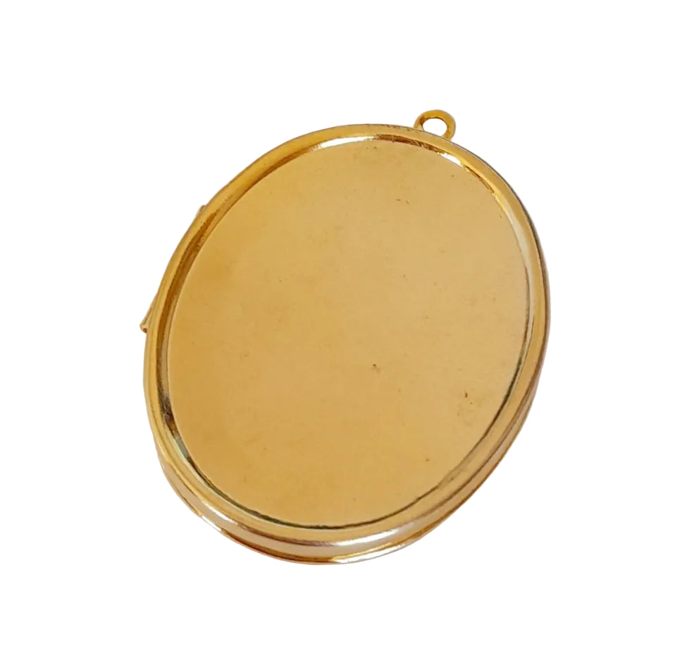An oval-shaped gold-toned metal pendant or locket with a small loop at the top, shown on a plain off-white background.