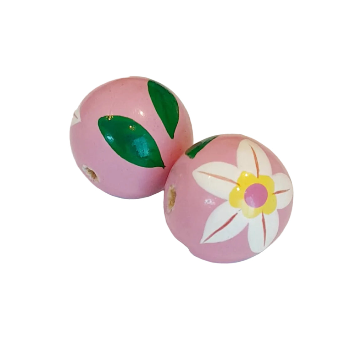 Two pink decorative wooden beads with hand-painted green leaves and a white flower with a yellow center,
