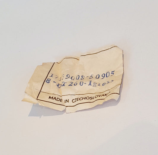 A crumpled beige paper tag with blue printed numbers and the text 'MADE IN CZECHOSLOVAKY' on a plain white background.