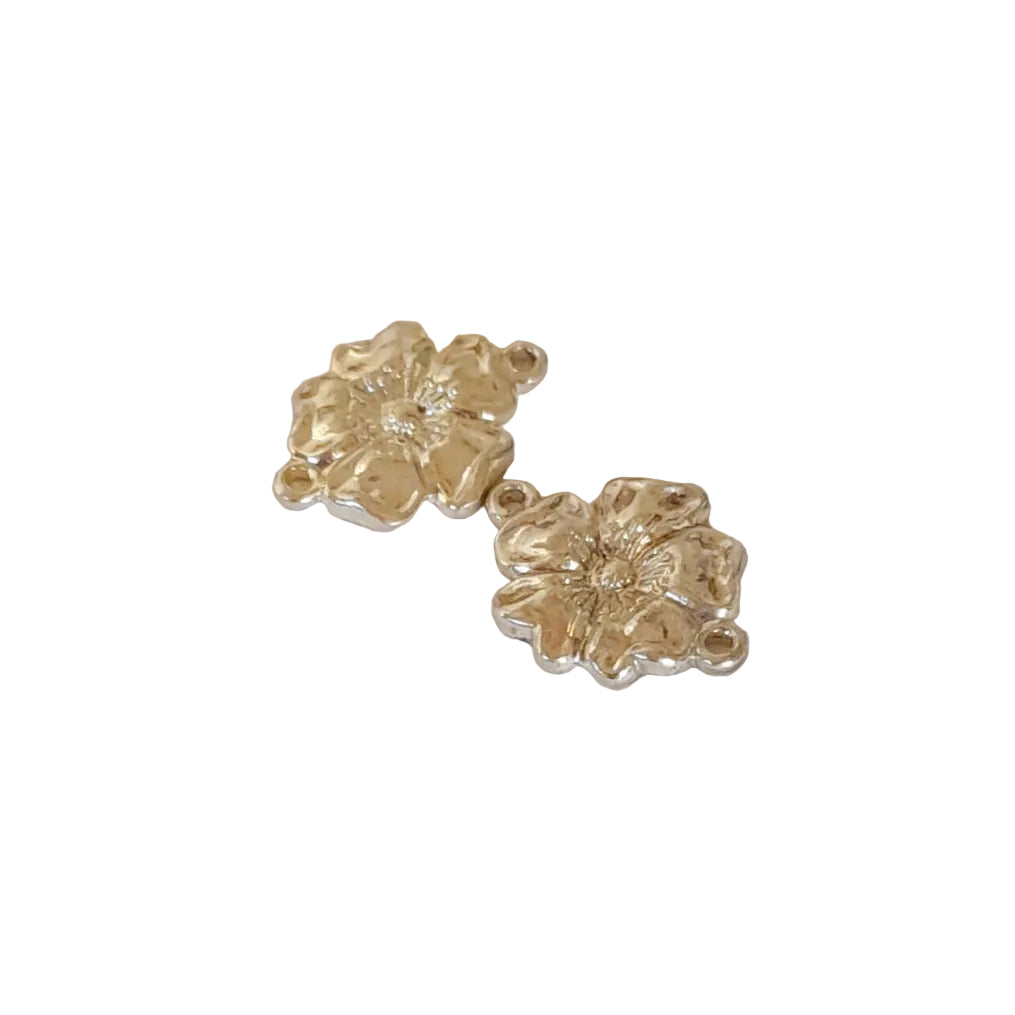 Two small silver flower-shaped jewelry charms with textured petals and small loops at the top and bottom