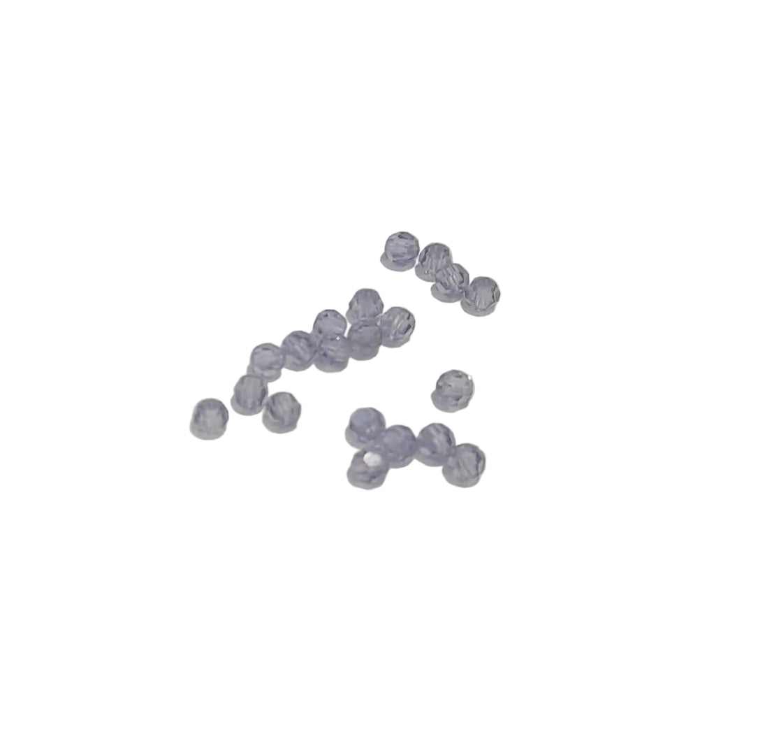 A small cluster of faceted lavender-blue beads scattered on a plain off-white background.