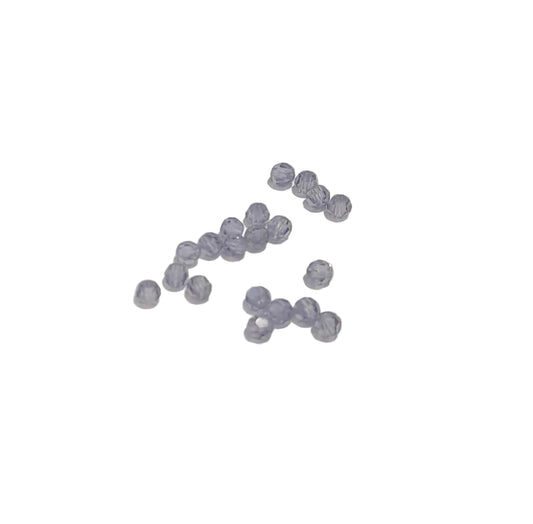 A small cluster of faceted lavender-blue beads scattered on a plain off-white background.