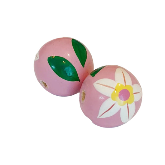 Two pink decorative wooden beads with hand-painted green leaves and a white flower with a yellow center, 