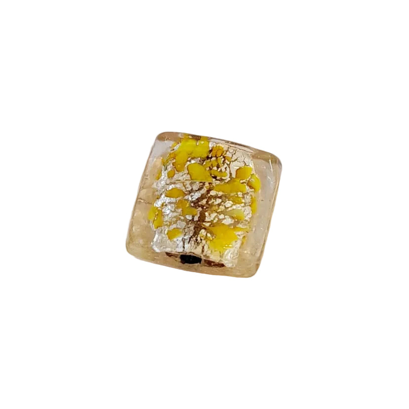 A square glass bead with a clear, slightly warm tint containing yellow and silver foil flecks, 