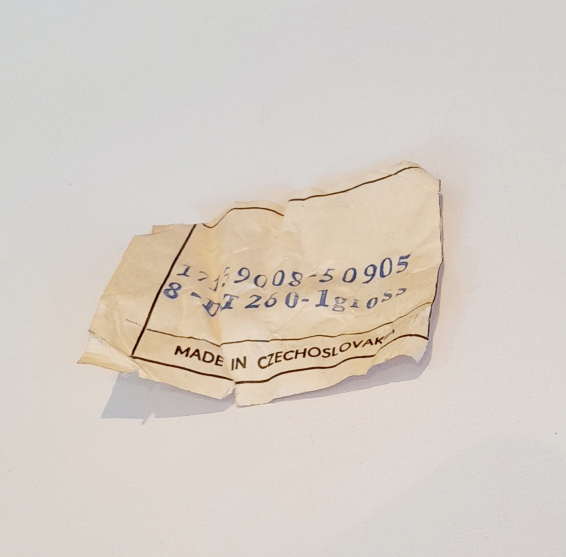 A crumpled beige paper tag with blue printed numbers and the text 'MADE IN CZECHOSLOVAKY' on a plain white background.