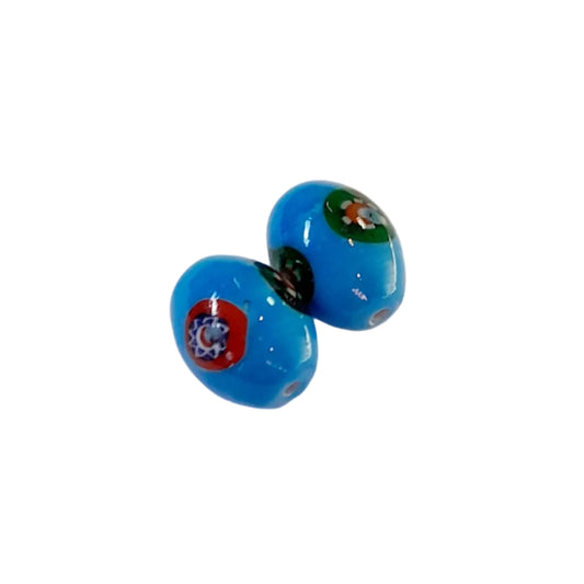 Two small glossy blue glass beads with colorful decorative motifs, shown on a plain white background.