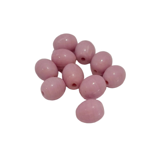 A cluster of glossy, oval-shaped pink beads with small holes, arranged on a plain off-white surface.