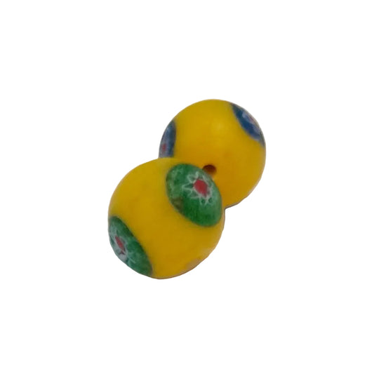 Two round yellow beads with hand-painted green, blue, and red Millefiori patterns, displayed on a plain white surface.