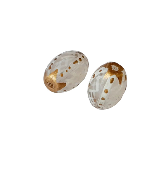 Two oval glass beads with a white and gold pattern,
