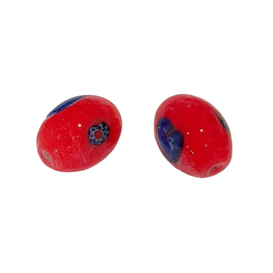 Two red glass lampwork beads with blue and white decorative details, displayed on a plain off-white background.