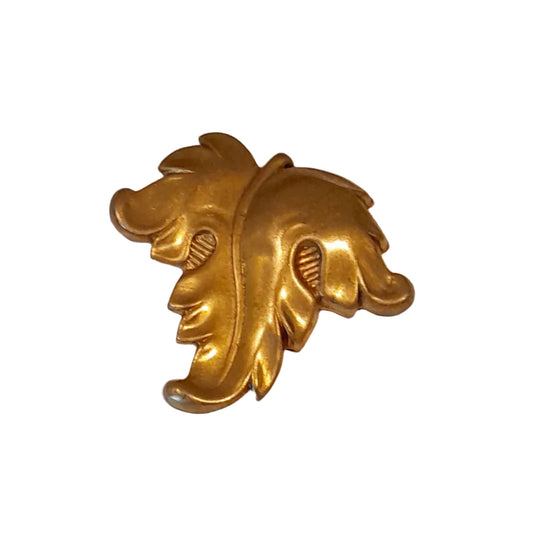 A large gold-toned decorative object with an ornate leaf or acanthus-like sculptural shape, 