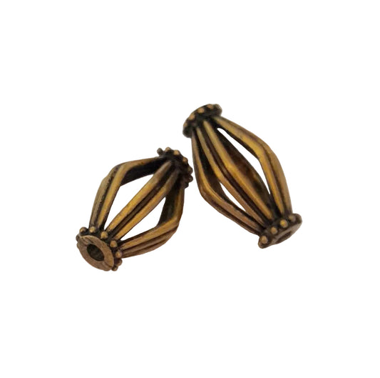 Two antique bronze metal spacers with a ribbed, geometric design, 