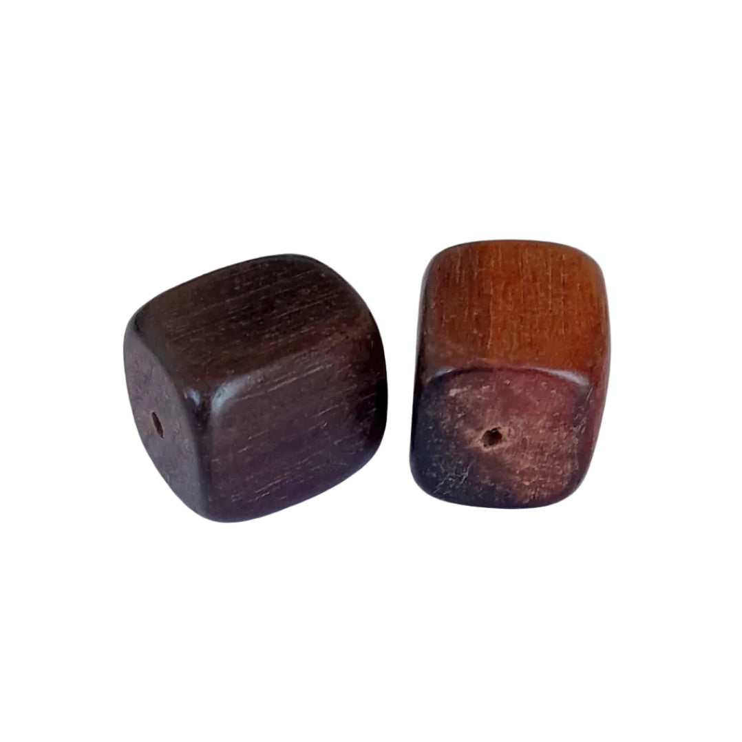 Two small wooden beads with rounded square shapes, one dark brown and one medium warm brown, each featuring a central hole, displayed on a light gray background.