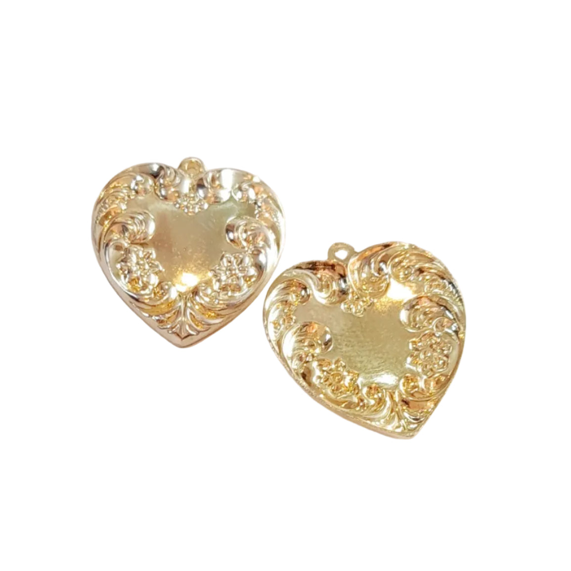 A pair of gold heart-shaped earrings with ornate filigree cutouts, displayed on a light off-white background.