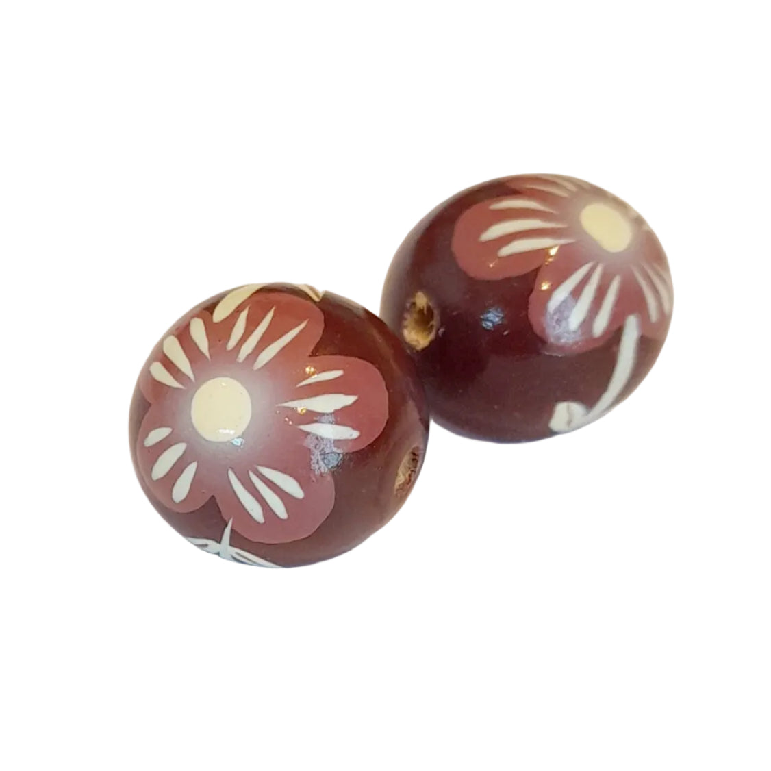 Two round wooden beads with a dark reddish-brown base, decorated with a white and dusty pink floral pattern, 