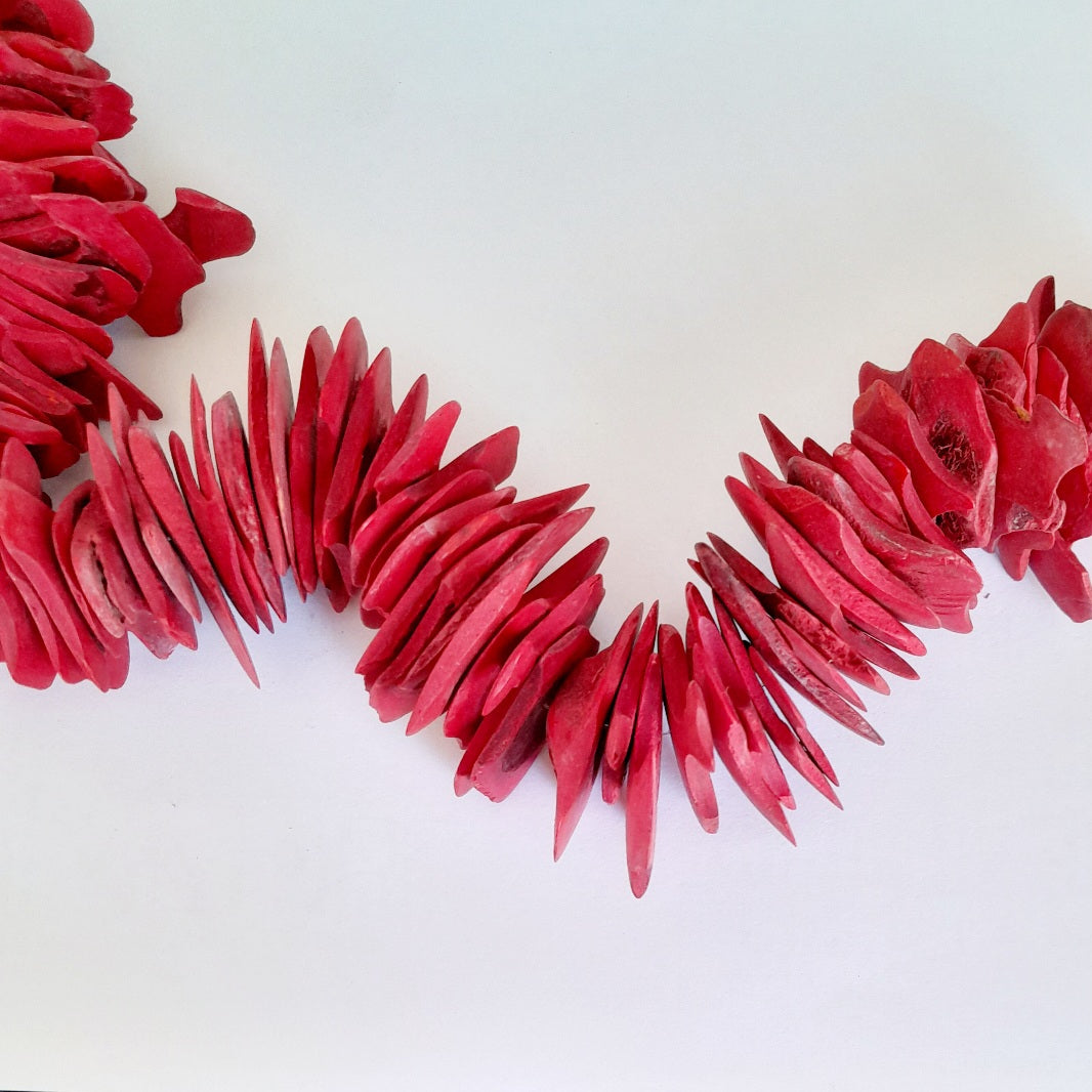 A strand of vibrant red coral-like wooden beads 