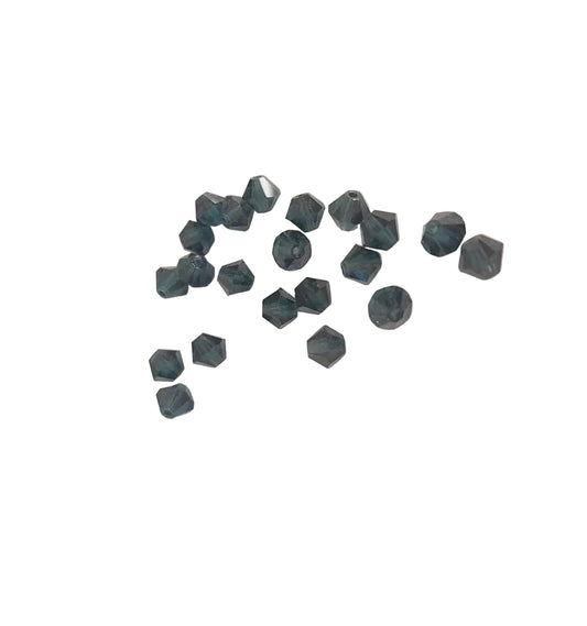 A group of small faceted dark blue-gray beads scattered on a plain off-white background.