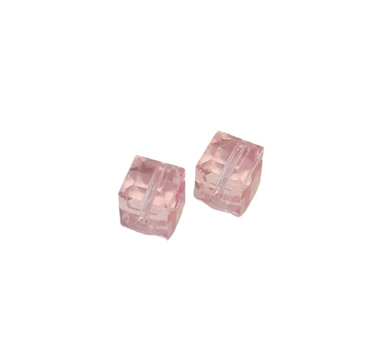 Two small translucent pink square beads with a faceted cut pattern, displayed on a plain off-white surface.