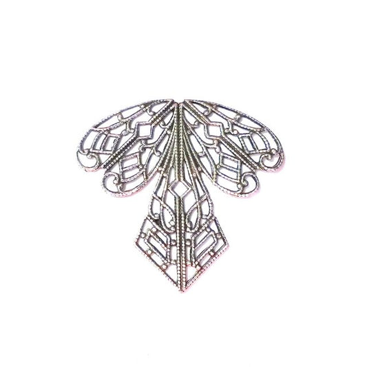 Antique silver plated brass stamping in the shape of a dragonfly with intricate details and a scalloped edge.